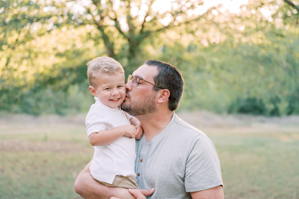 dad kisses toddler son on cheek