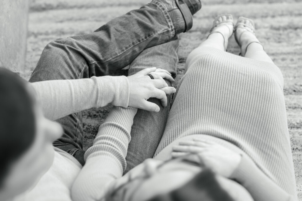 husband and wife hold hands while mom holds baby bump 