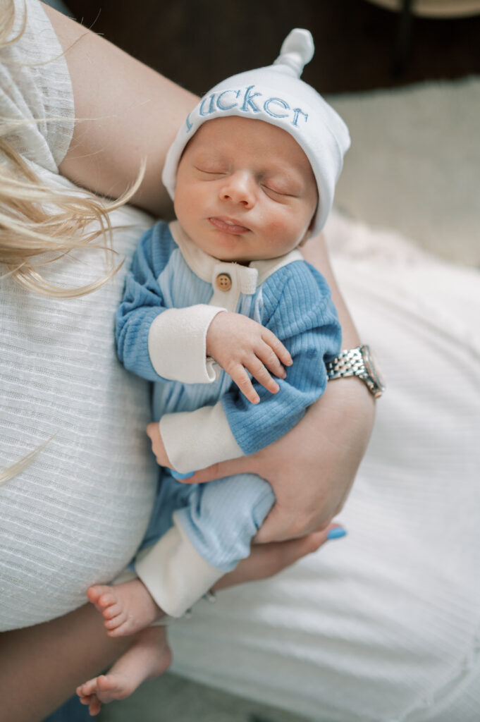 baby lays in mom's arms and sleeps during in-home newborn session
