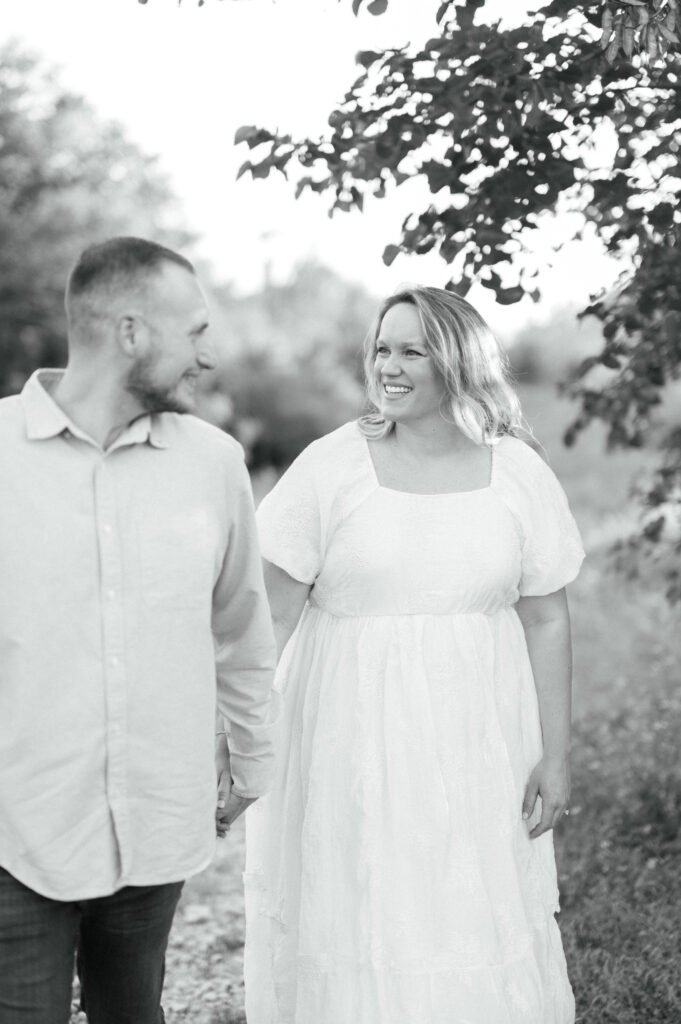 husband and wife walk while looking at each other during maternity session