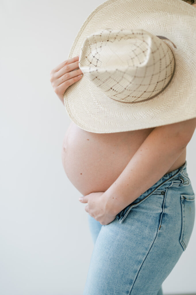 hat covers up everything but baby bump during studio maternity photos