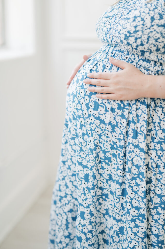 mom touches baby bump during studio maternity session in fort worth