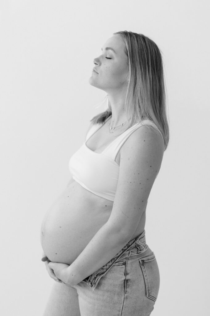 mom looks up while holding baby bump during studio maternity photos