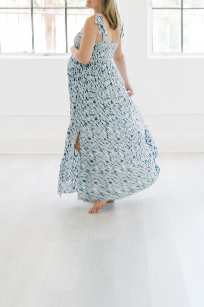 mom twirls in long dress while holding baby bump during studio maternity photos