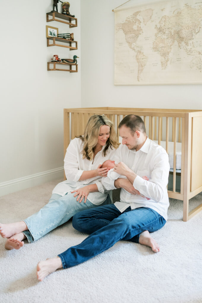 at home newborn session mom and dad hold baby in nursery
