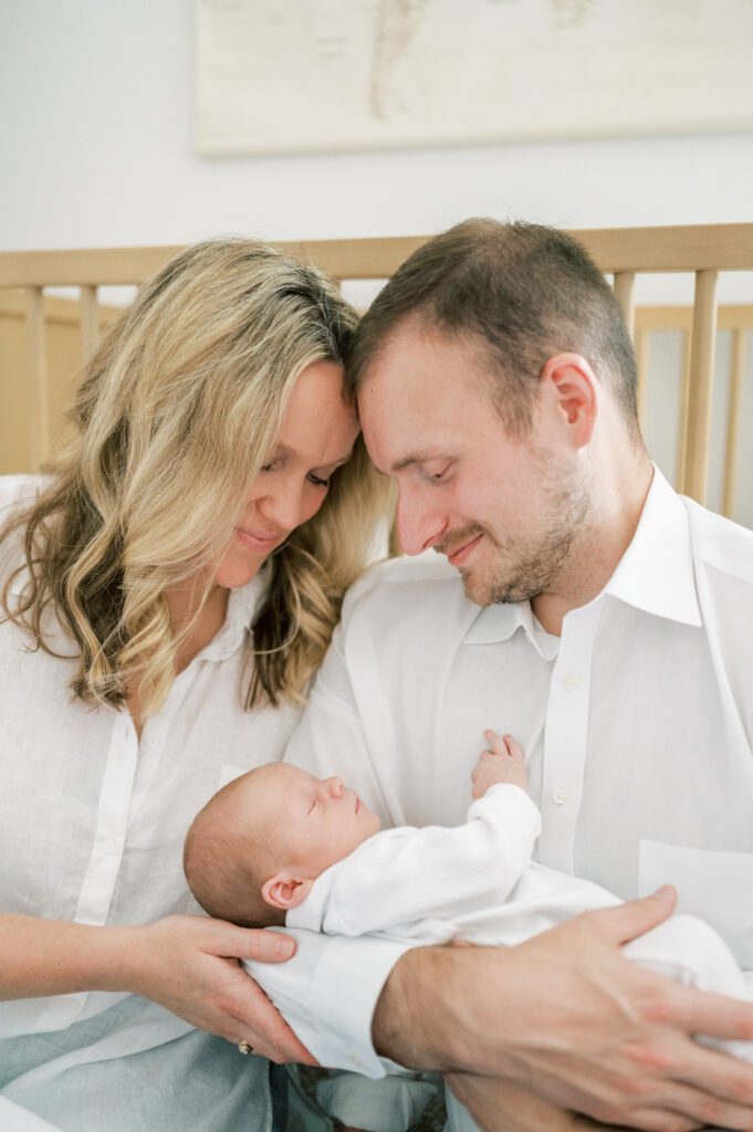 at home newborn session parents hold baby in nursery