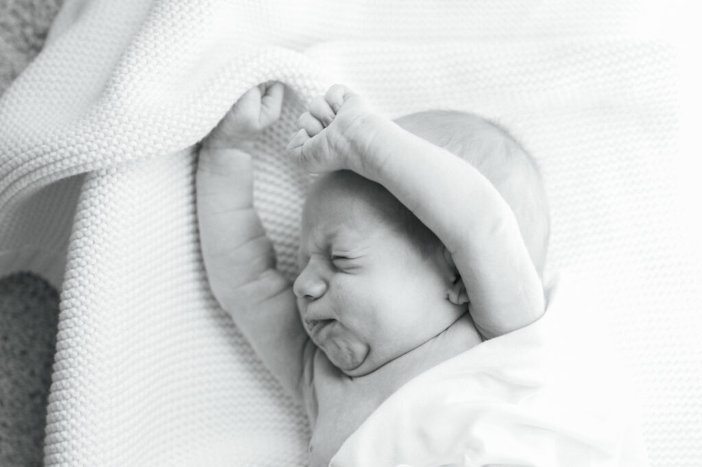 at home newborn session photo of baby stretching