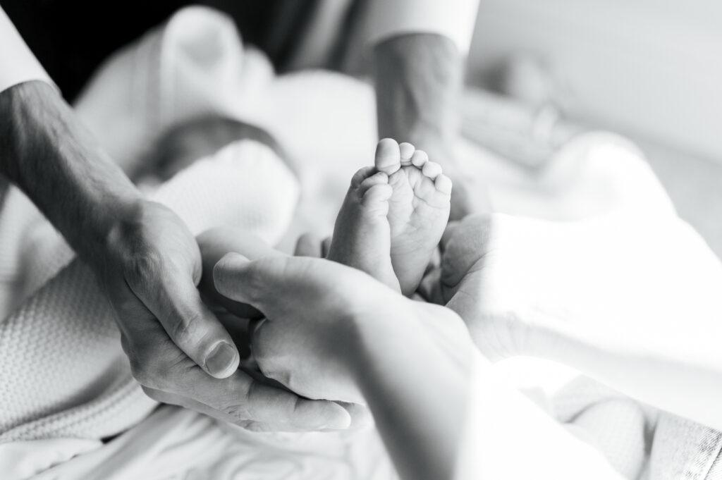 mom and dad hold newborn feet during at home newborn session