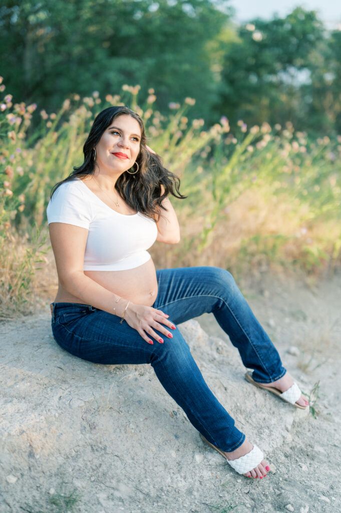 expecting mom sits in sun and touches hair