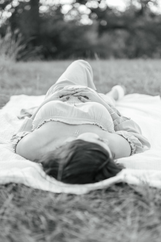 mom lays in field holding baby bump