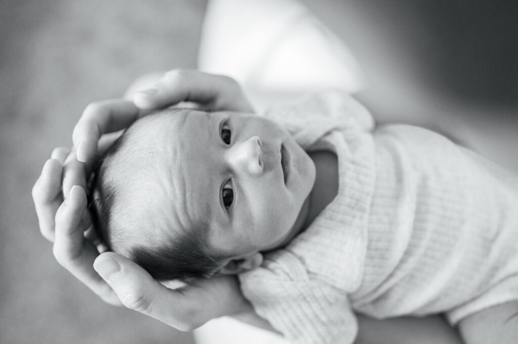 lifestyle newborn photography, baby stares up with eyes wide open