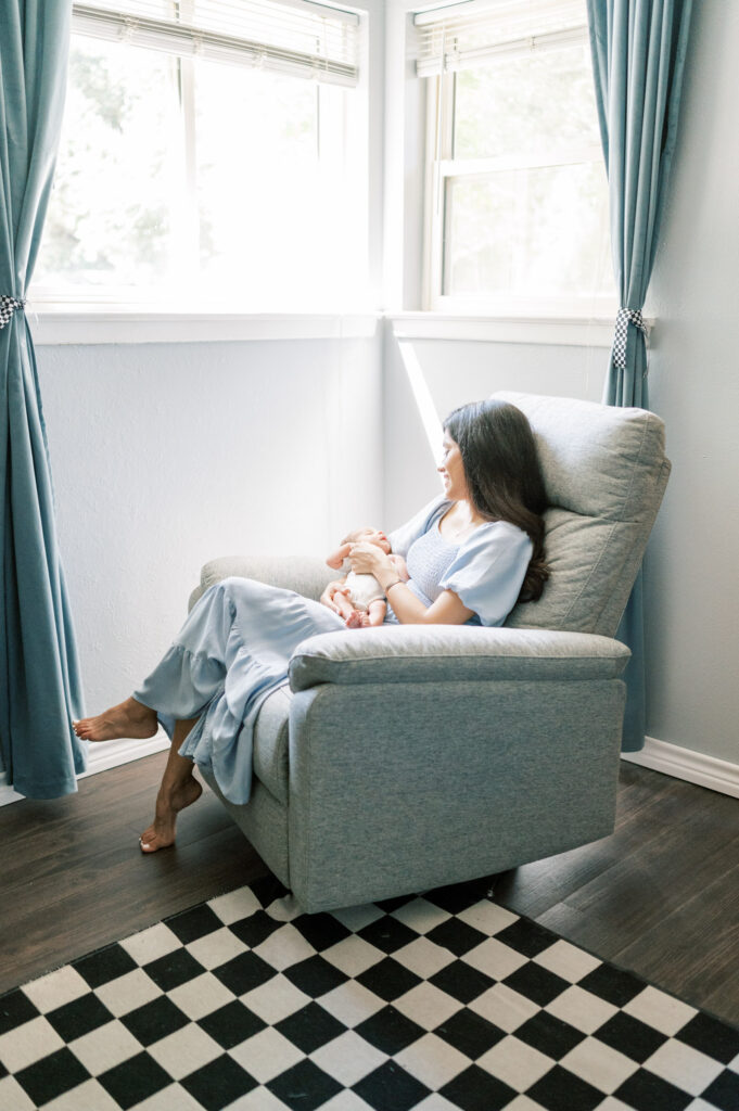 lifestyle newborn photography session, mom rocks baby by window in nursery