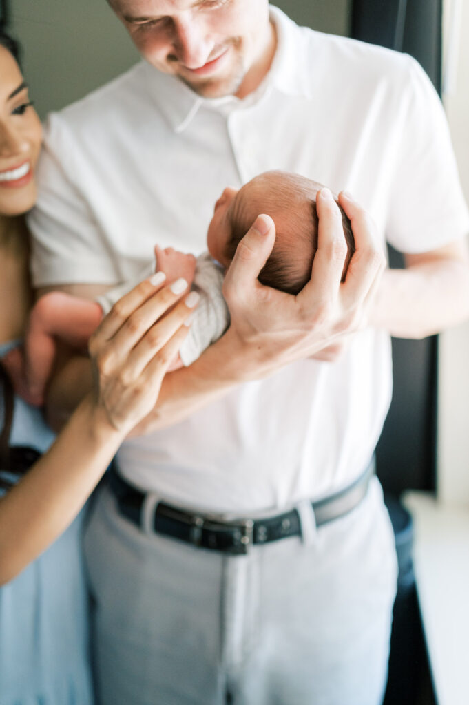 lifestyle newborn photography, mom and dad hold baby newborn
