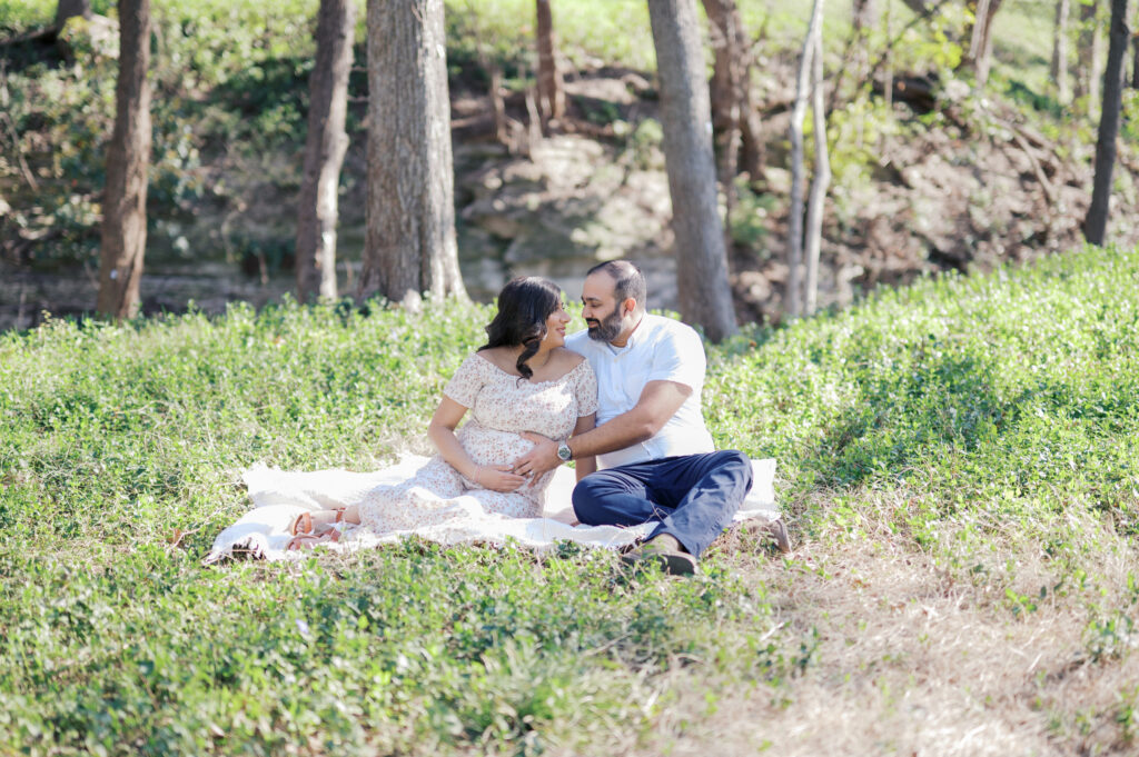 maternity photos in dallas, expecting parents sit on blanket in green space