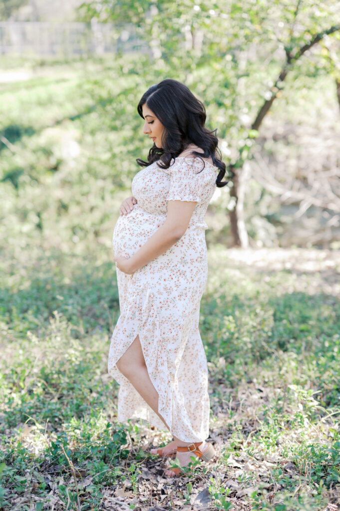 expecting mom embraces bump surrounded by greenery in dallas park
