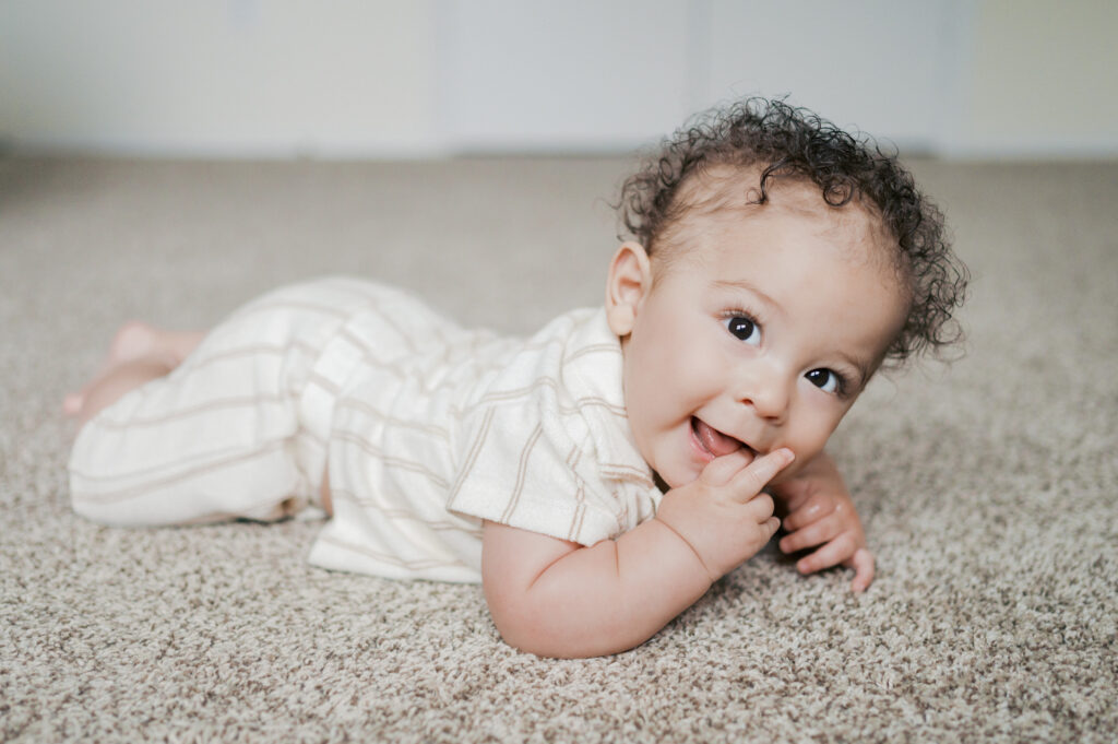 milestone portrait of baby boy laying on belly and smiling 