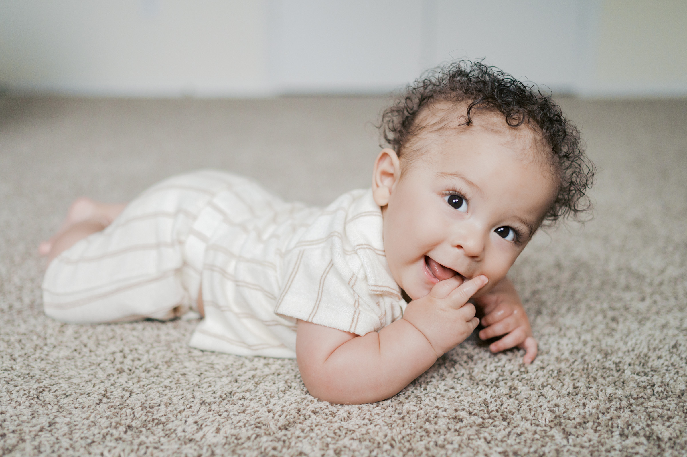 milestone portrait of baby boy laying on belly and smiling