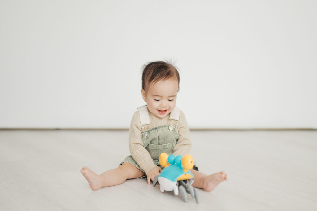little boy plays with toy and smiles in a studio