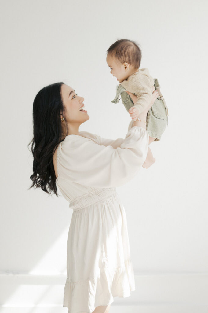 mom raises baby boy up and smiles at him