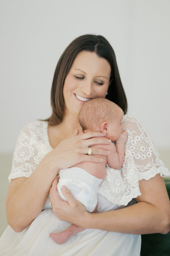 mom snuggles newborn girl in studio