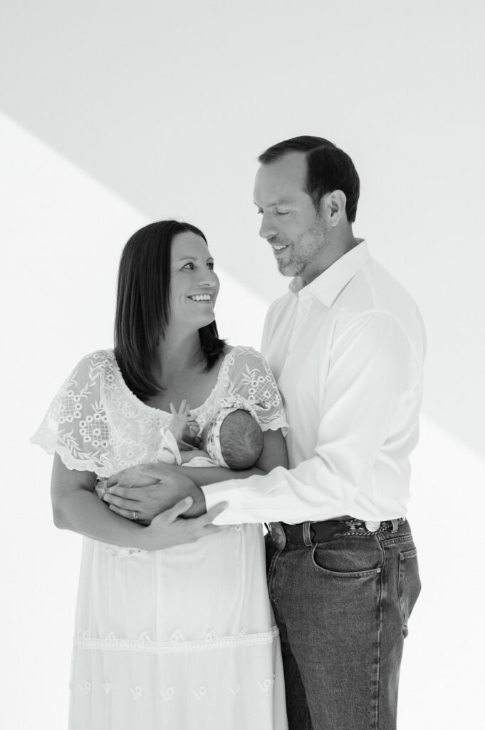 mom and dad look at each other while holding newborn daughter