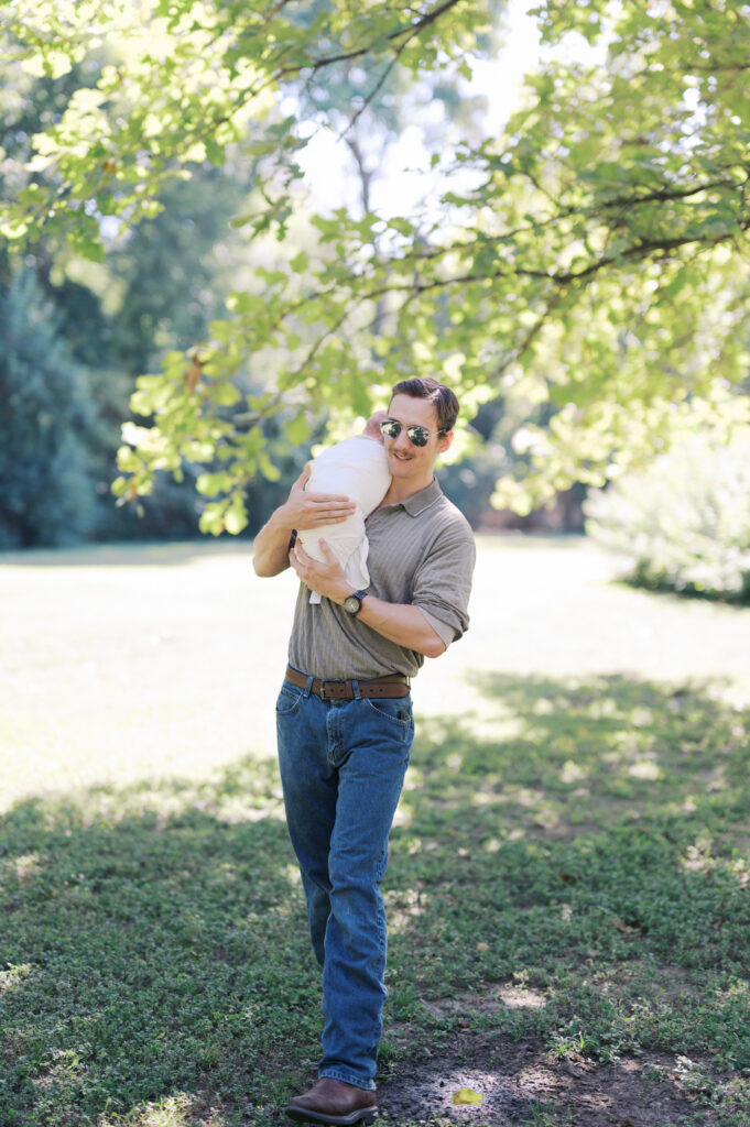 dad walks with swaddled newborn baby outside