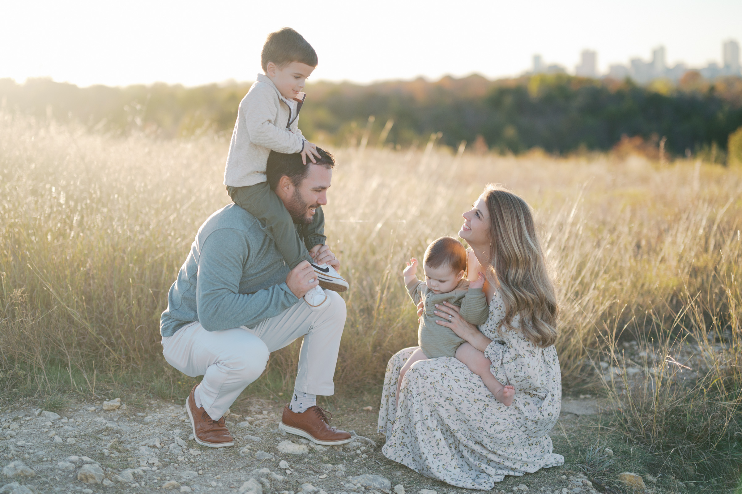 family kneels in tall grass in fort worth during outdoor family photos in fort worth