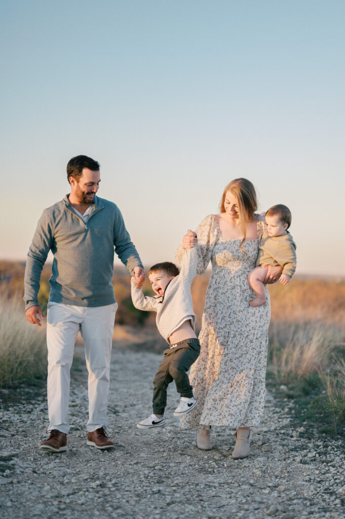 family walks and little boy in middle jumps up while walking