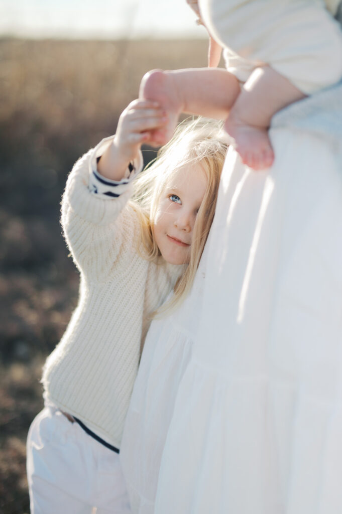 little girl touches sister's toes in sunlight