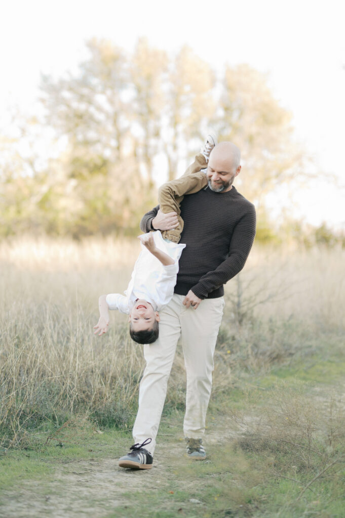 dad playfully carries son upside down during family photos in north fort worth
