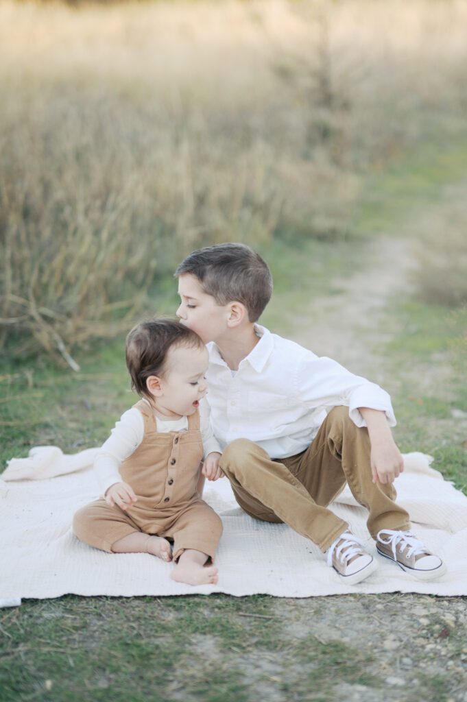 two brothers sit on a blanket during family photos