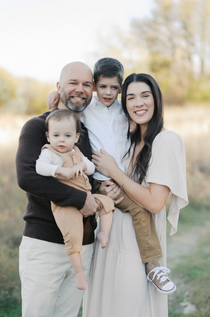 family of four smiles at the camera during family photo session 