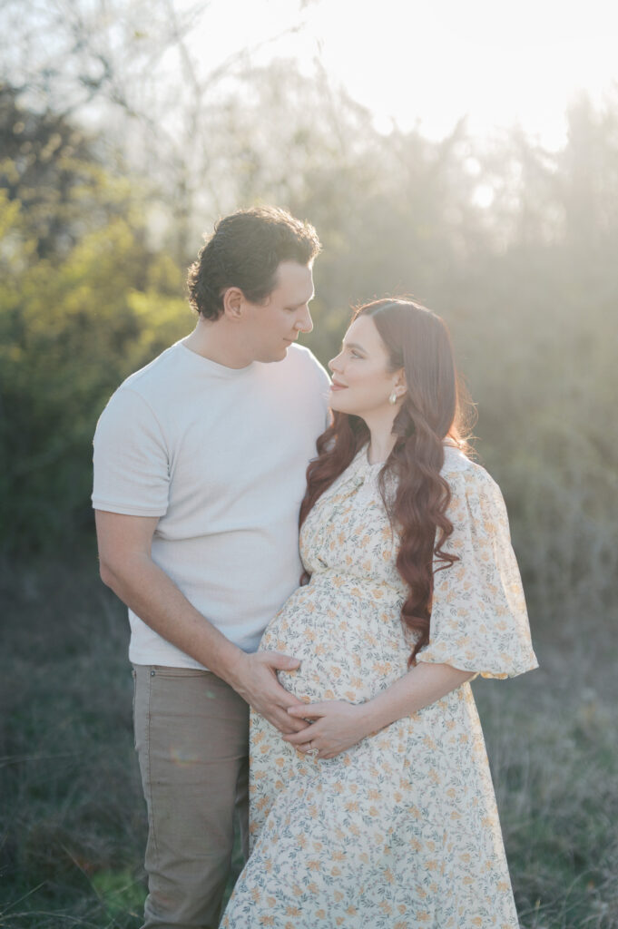 expecting parents look at each other during maternity photography session in north fort worth