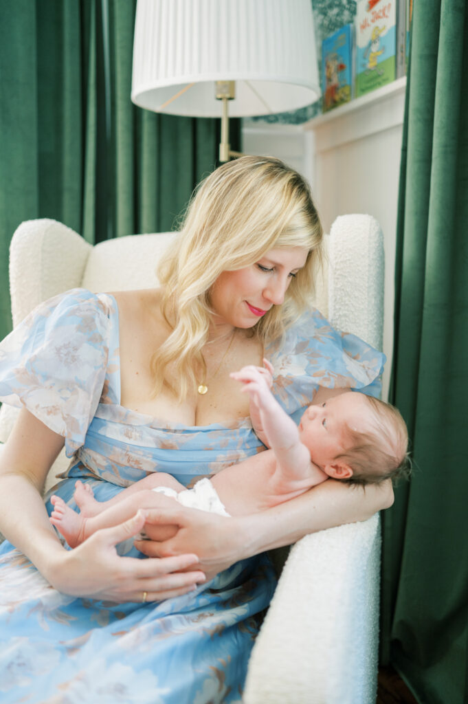 mom looks down at newborn baby boy in nursery