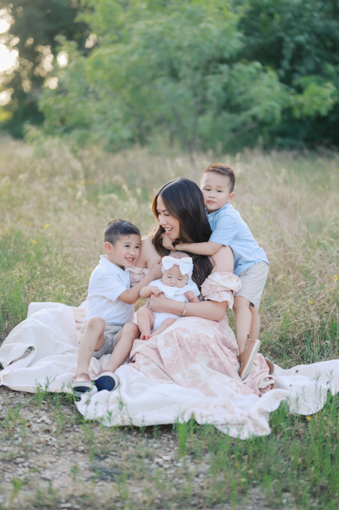 3 kids snuggle close to mom outdoors 