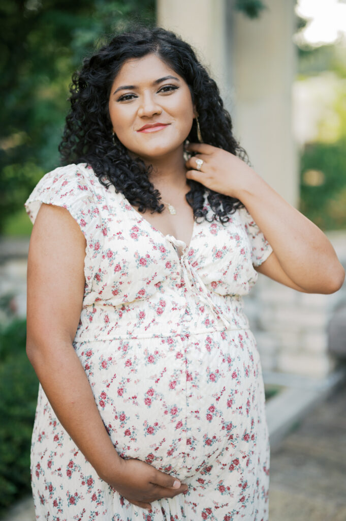 mom smiles at camera while moving hair during maternity session