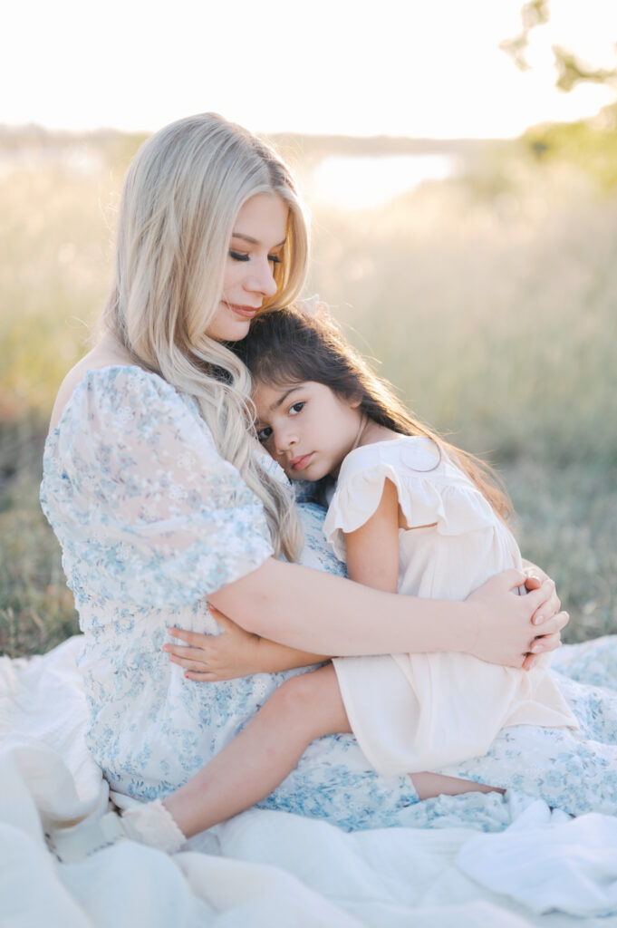 child snuggles with mom during maternity photos outdoors