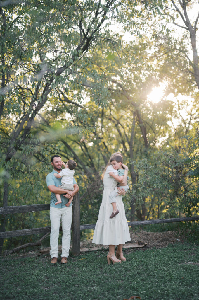 family of four stands in sunlight during family photography session