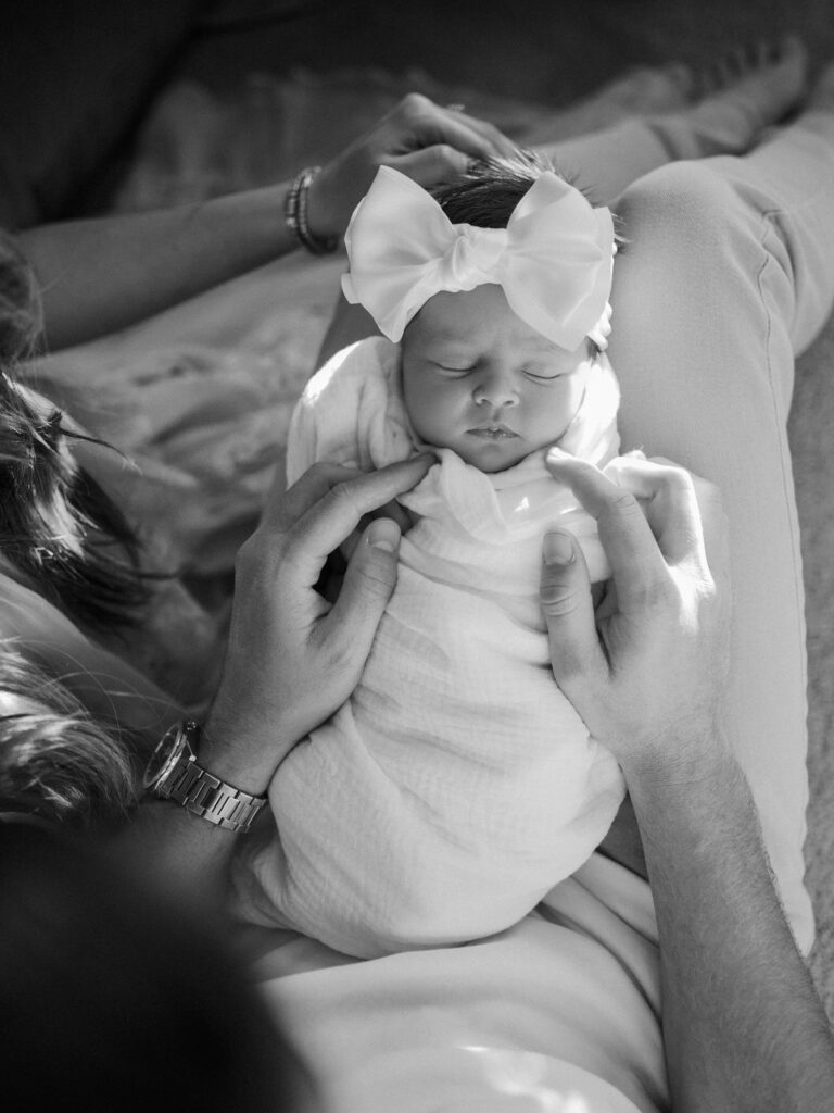 baby rests in mom and dad's arms during newborn photos