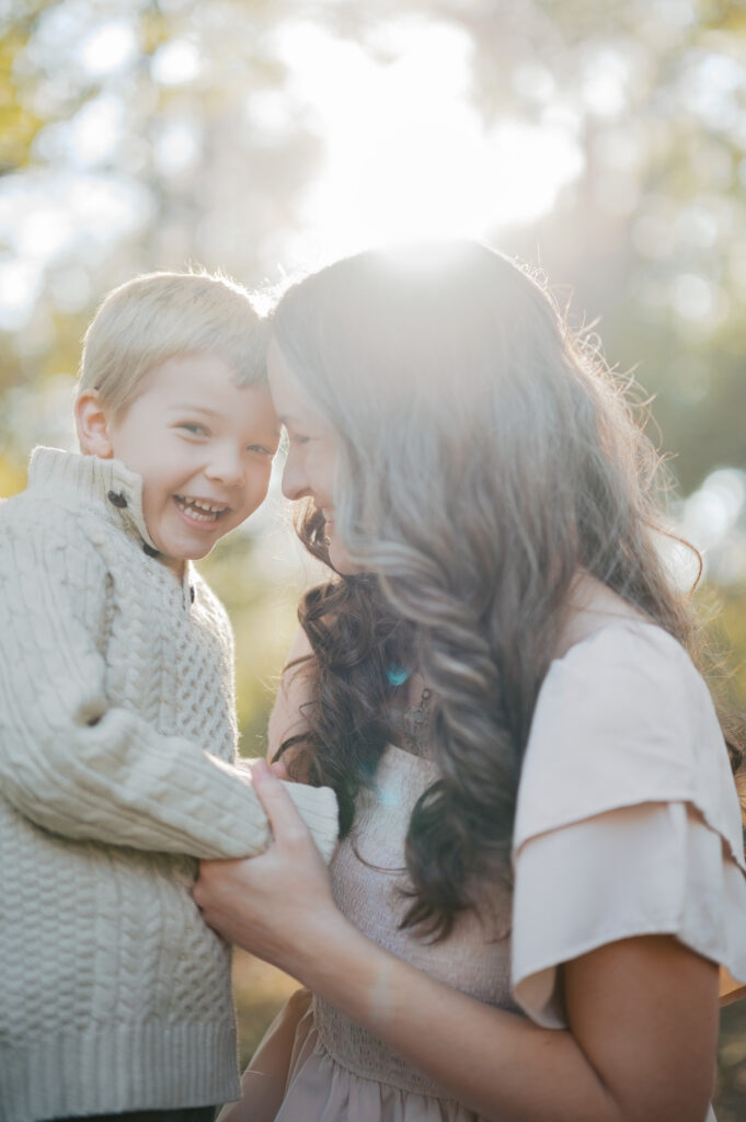 mom snuggles with son in the sunlight at the fort worth botanic garden