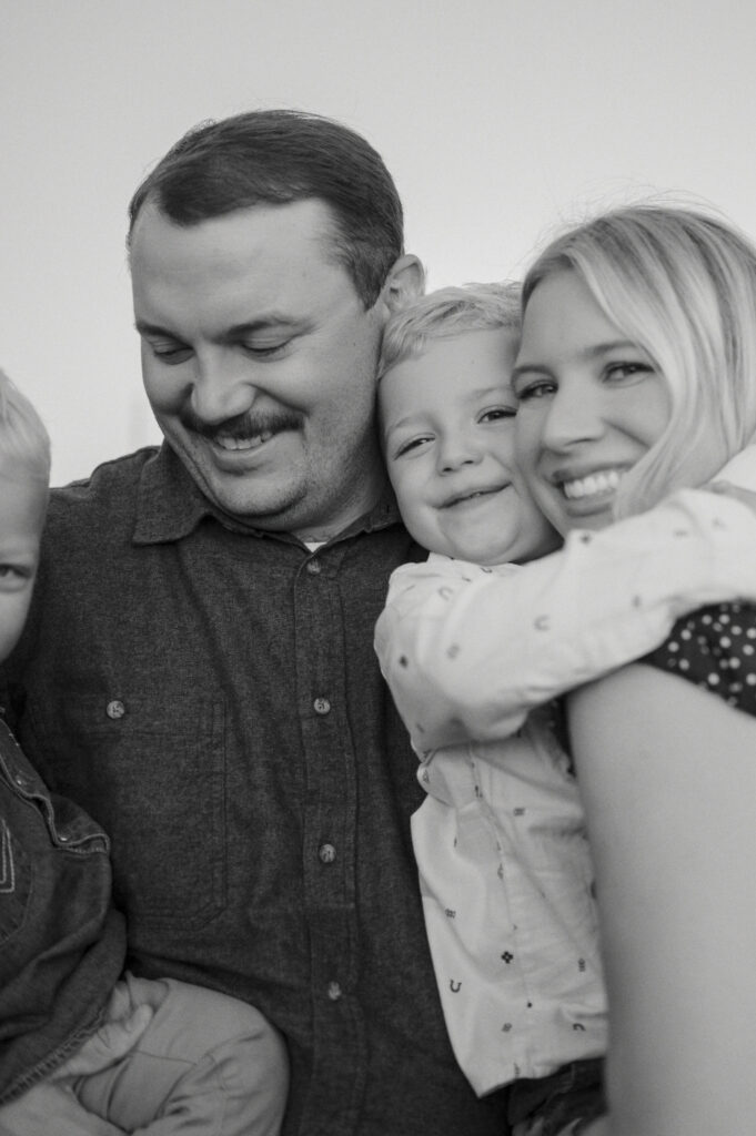 family gathers close and hugs during family photos with toddlers in fort worth