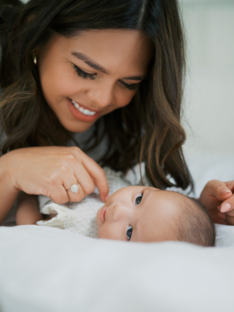 mom looks down lovingly at baby girl during newborn photos at the beverly harris house