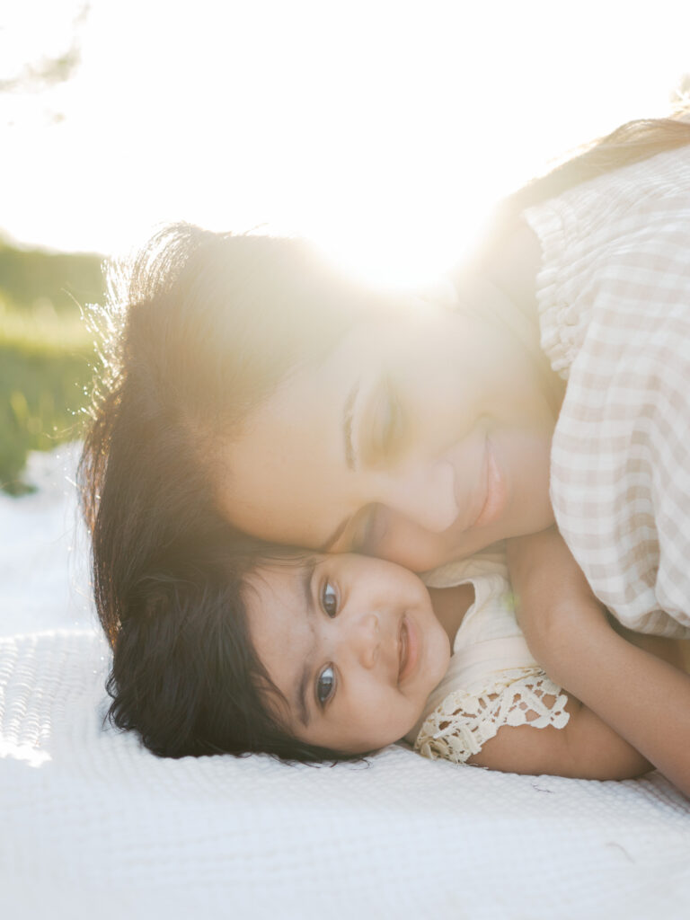 mom snuggles six month old outdoors at a fort worth park during milestone photos