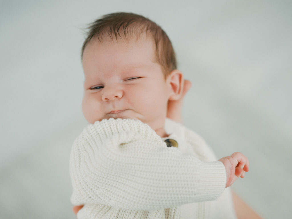 fort worth newborn session lifestyle, baby lays in moms arms with scrunched up face