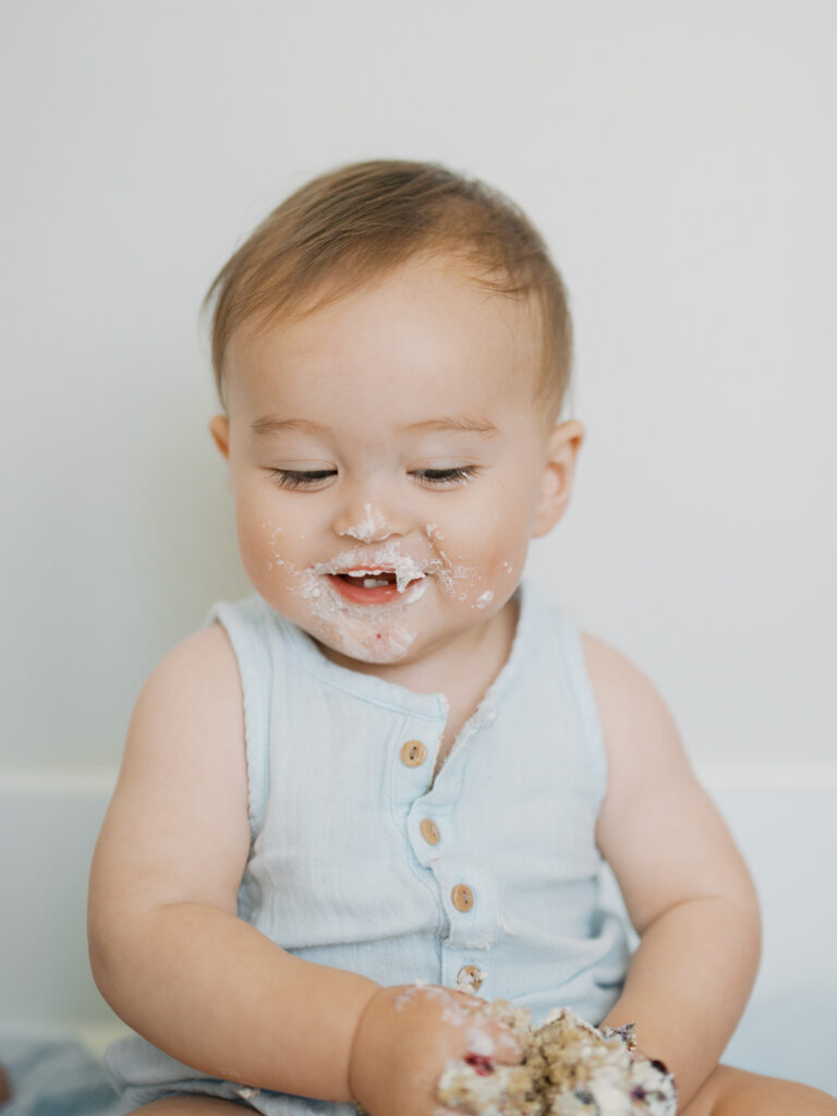 baby boy smiles during cake smash photo session at home in argyle 