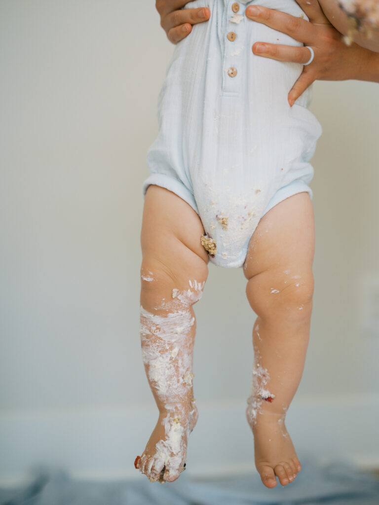 frosting on baby boy after one year milestone cake smash photos