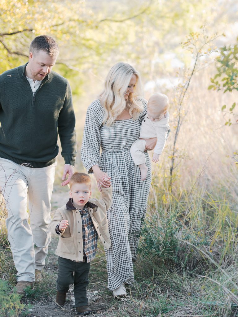 family of four walks through tall grass during a fall family photography session in fort worth