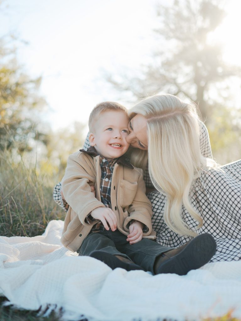 mom snuggles with young son during family photography session outdoors