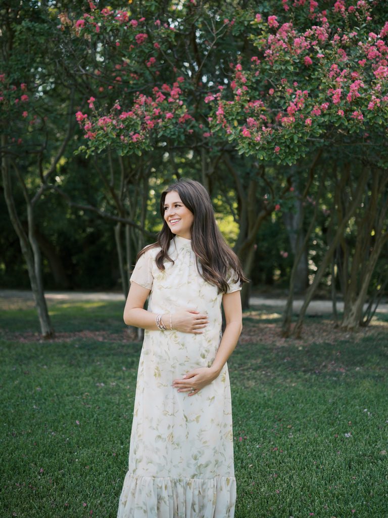 expecting mom holds baby bump during announcement photos at fort worth botanic garden