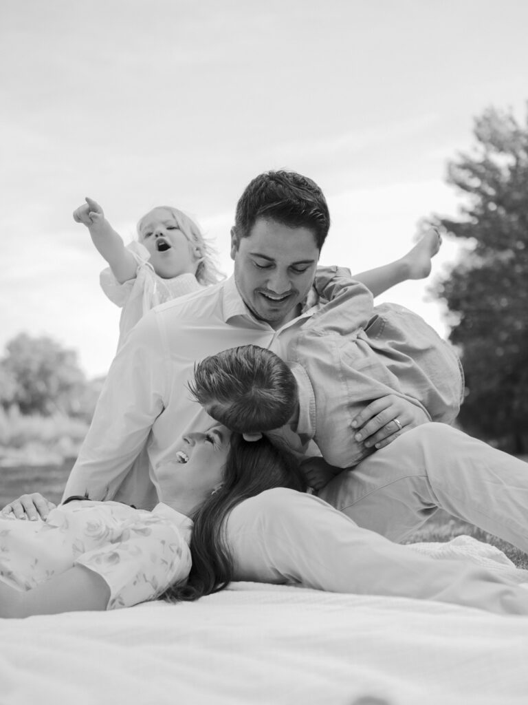 family of four piles together on a blanket during family photos at botanic garden